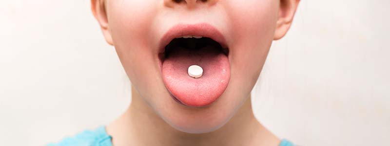 Child with pill on tongue