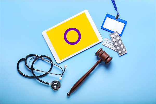 Intersex flag on ipad with stethoscope, gavel, medication, and name tag.