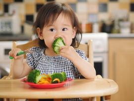 baby girl eating vegetable at home