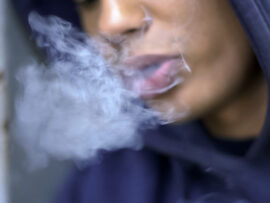 Teenage boy smoking leaned up against doorframe
